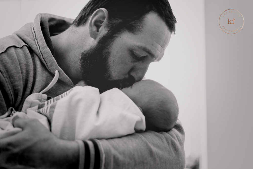 lapeer dad kissing newborn baby for hospital picture by kat fantin photography